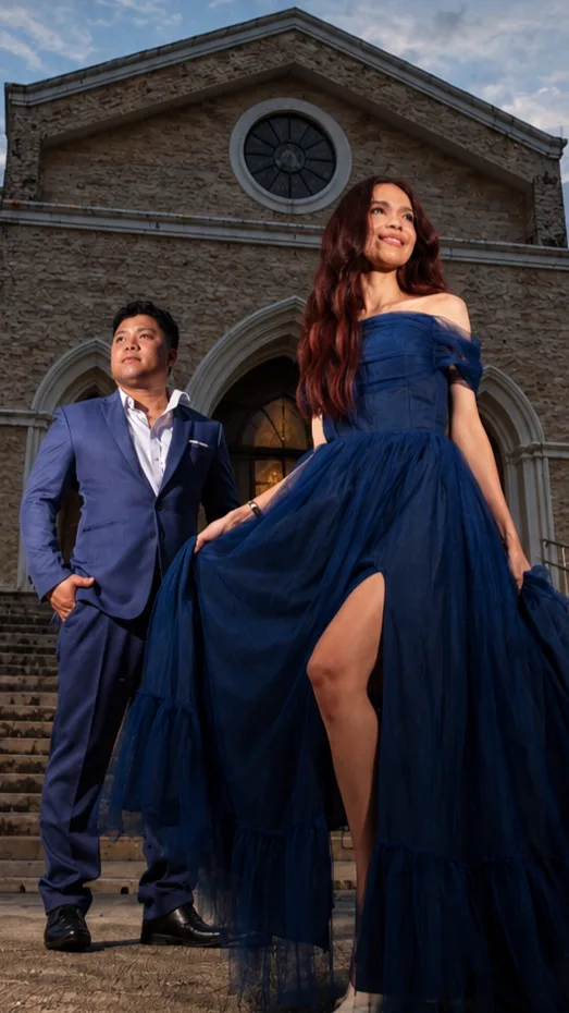 Cid and Jas in formal wear in front of a stone church